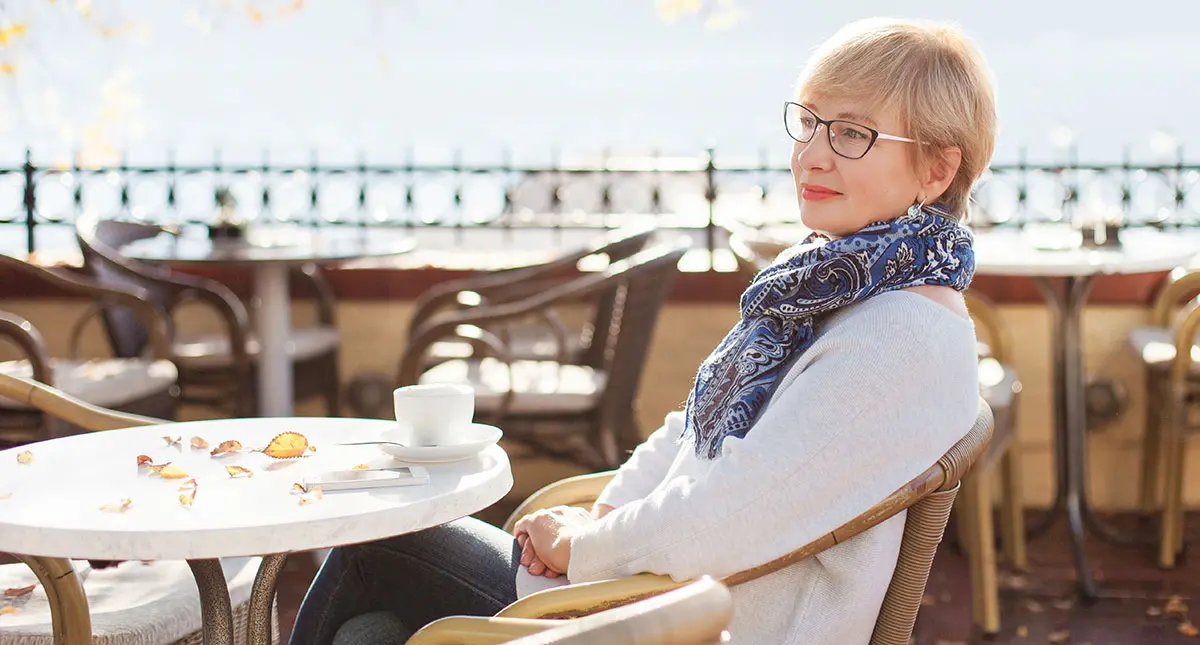 woman sitting at outdoor table with a cup of coffee