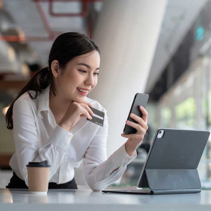 Woman holding a credit card and looking online shopping.