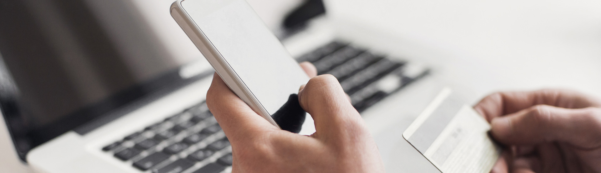 Person holding a credit card while looking at a laptop