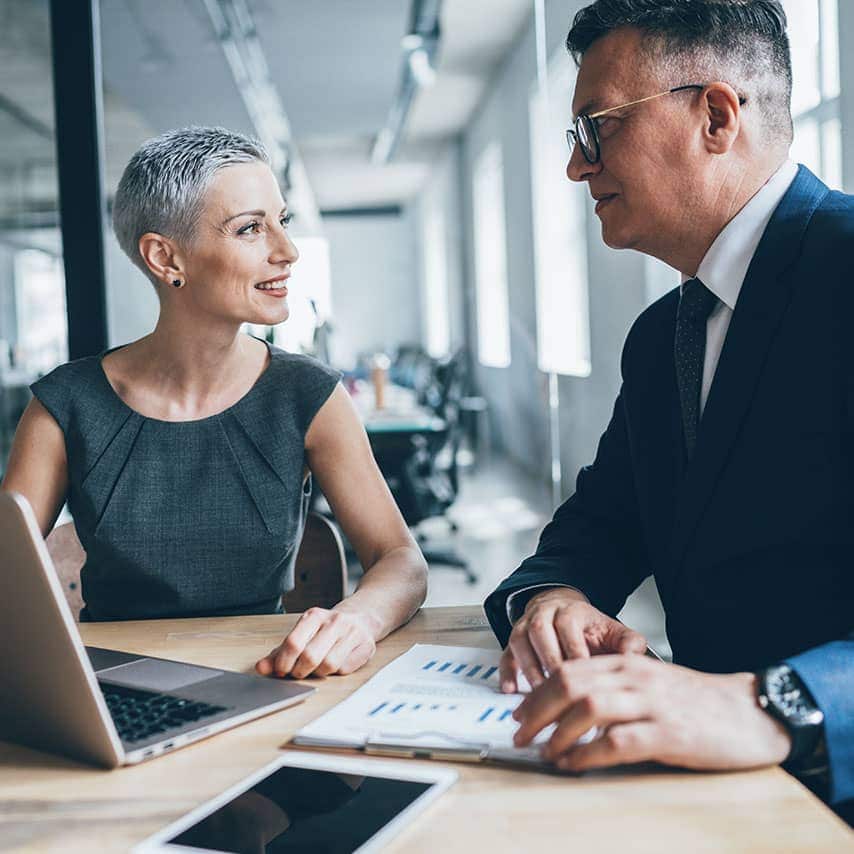 Two coworkers, a man and woman, discussing business in their office