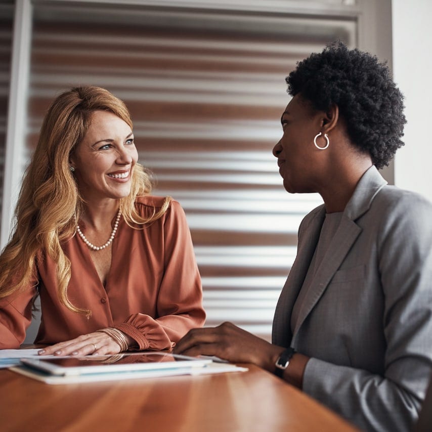 Two professional women conversing at a table