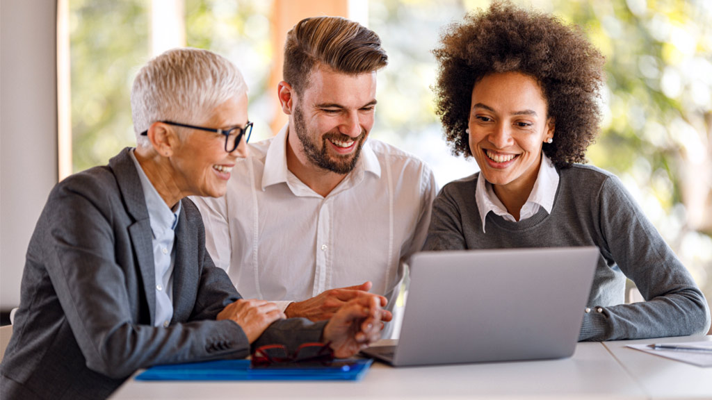 Three individuals having a discussion around a laptop